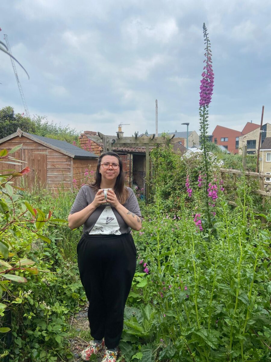 Christina stood in her wild garden with a cup of tea and a enormous foxglove